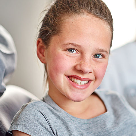 Tween girl smiling at camera from dental chair